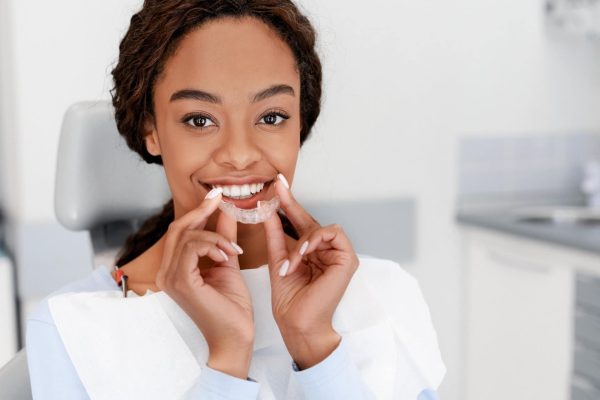Dental Treatment Concept. Close up of young black woman holding invisible aligner, whitening tray, free space